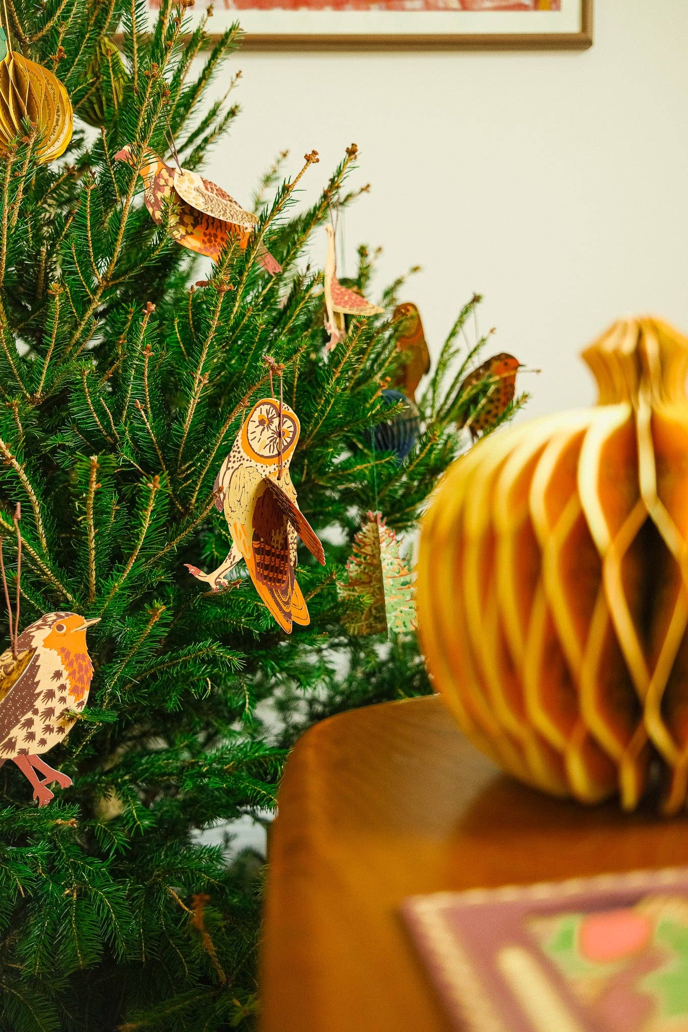 Decorative Christmas tree with ornaments and a pumpkin on a table.