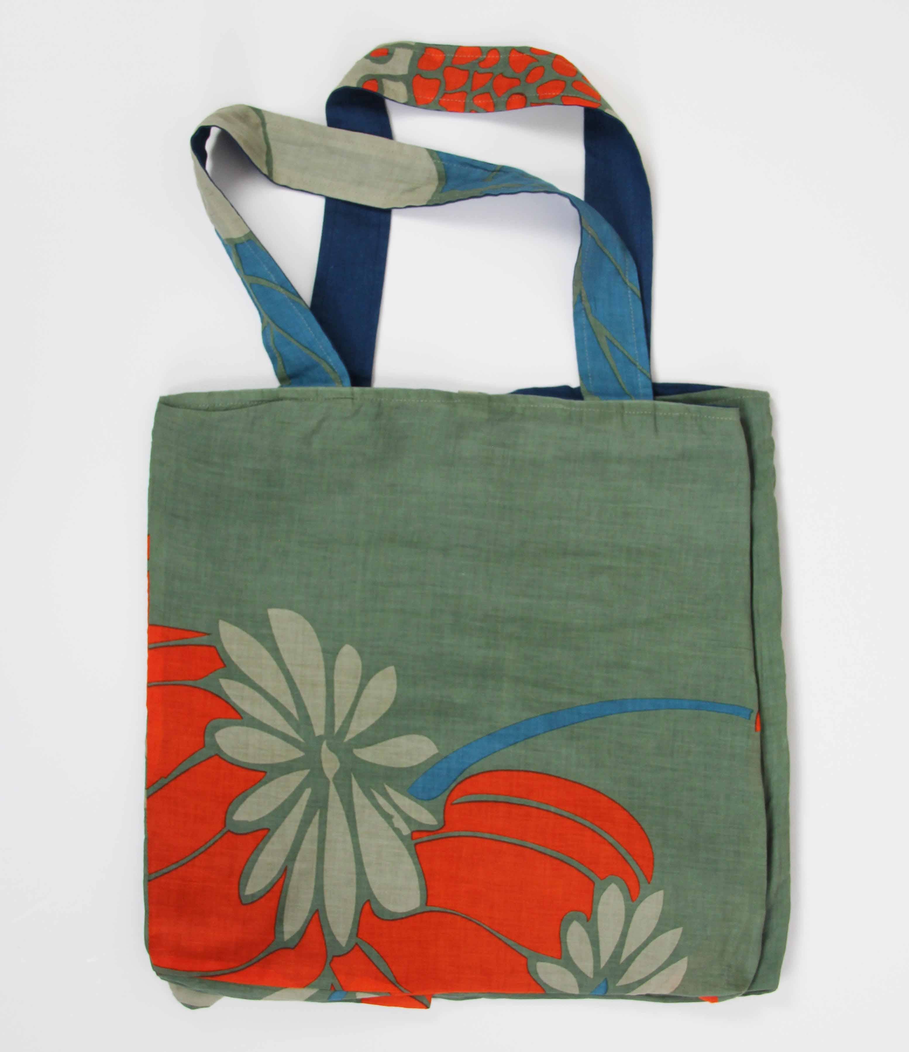 Green tote bag with floral designs on a white background