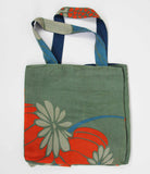 Green tote bag with floral designs on a white background