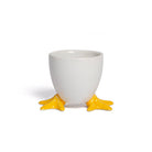 White ceramic egg cup with yellow feet on a white background