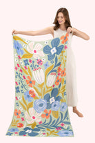Woman holding a large floral-patterned fabric with colorful flowers on a white background