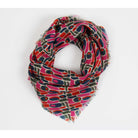 A lightweight scarf with a colorful abstract geometric pattern, featuring pink, red, navy, and olive green shapes on a cream background with fringed edges, shown on a plain white background.