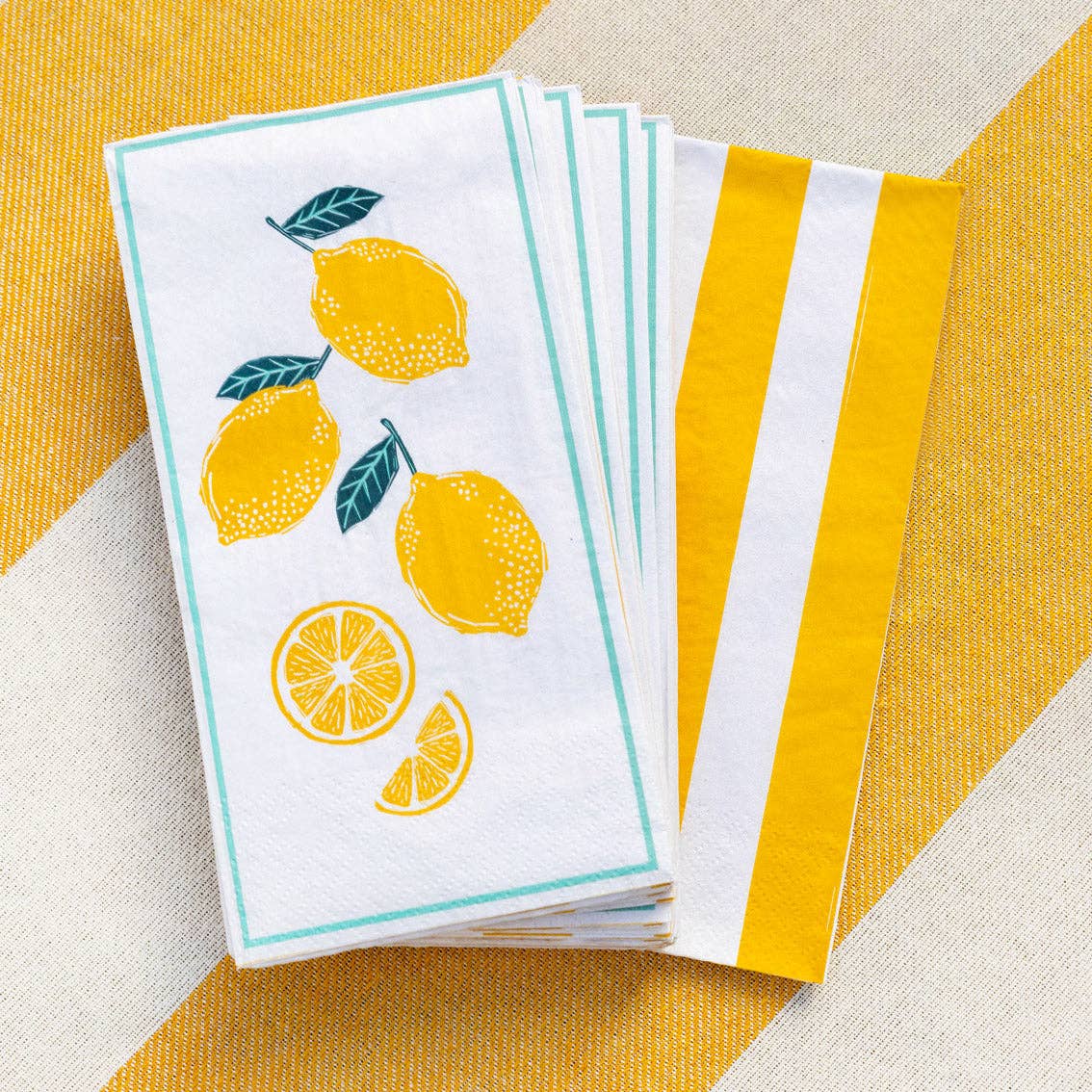 Set of white towels with lemon designs on a yellow and beige striped background