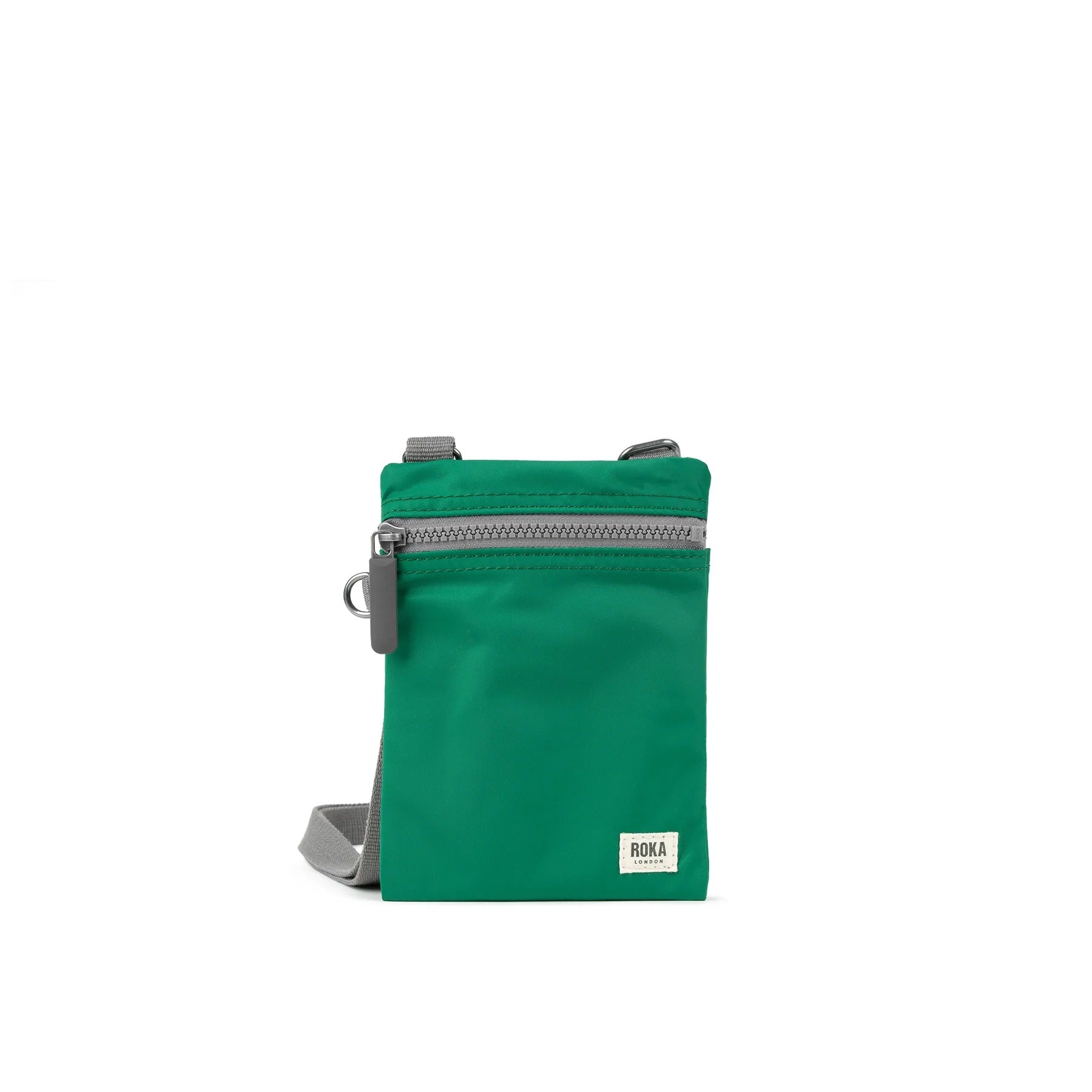 A photo of the front of a small rectangular emerald green pocket bag. It has a grey zip horizontally at the top, grey straps, and a small ROKA logo in the bottom right corner.