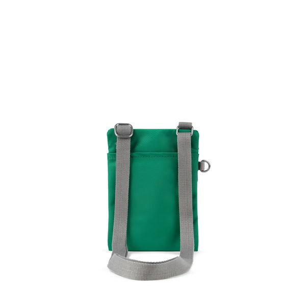 A photo of the back of a small rectangular emerald green pocket bag. It has a pocket and grey straps.