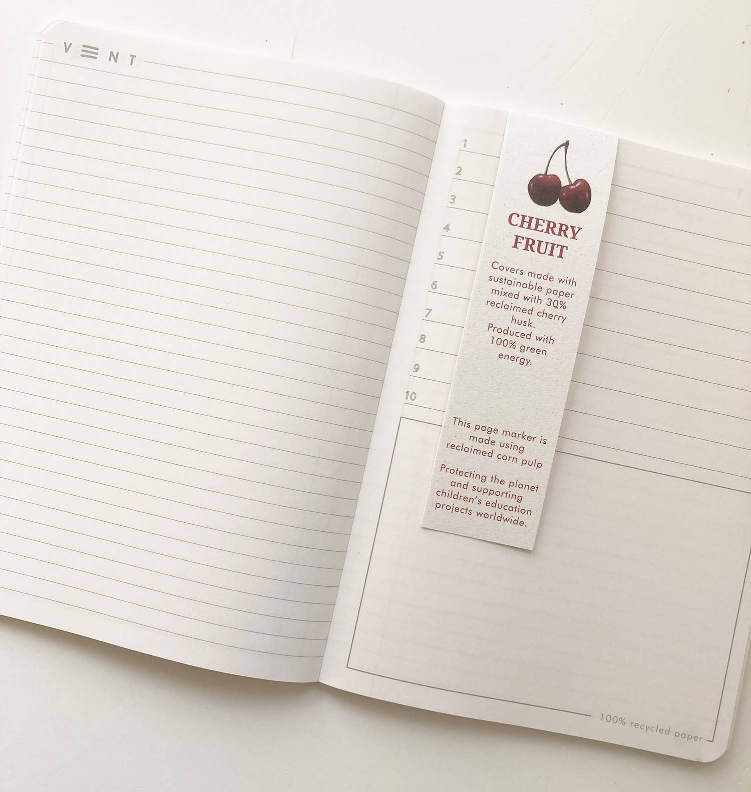 Open notebook with a cherry fruit-themed page marker on a white background