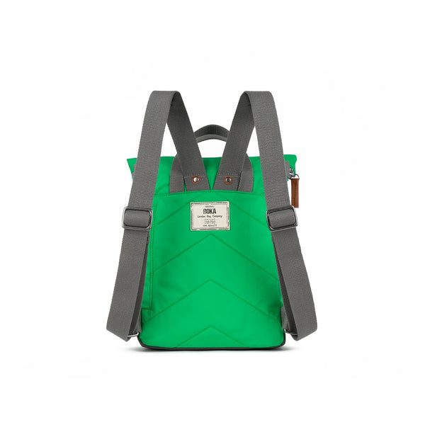 Photo showing the back of a small bright green coloured backpack. The straps and handles are grey and there’s a small fabric label with the ROKA logo on.