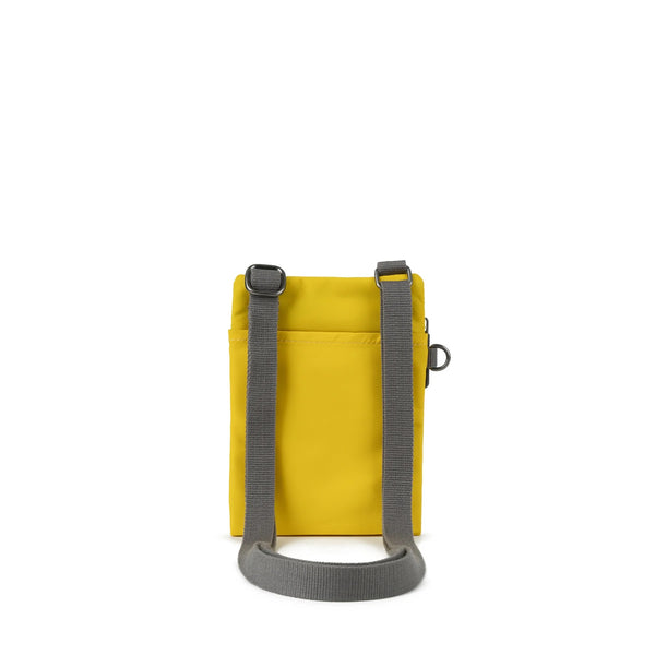 A photo of the back of a small rectangular yellow pocket bag. It has a pocket and grey straps.