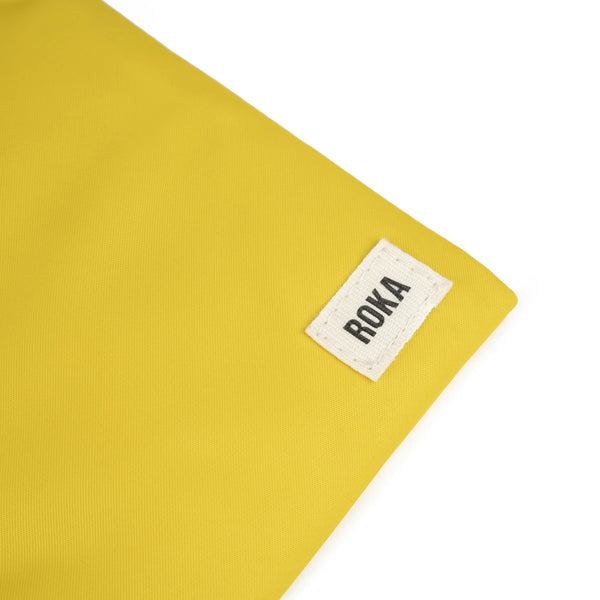 A close up photo of the bottom corner of a yellow bag, showing the ROKA London label.