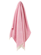 Pink blanket with white fringe on a beige background