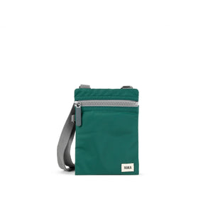 A photo of the front of a small rectangular teal pocket bag. It has a grey zip horizontally at the top, grey straps, and a small ROKA logo in the bottom right corner.