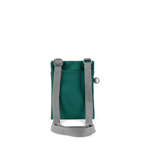 A photo of the back of a small rectangular teal pocket bag. It has a pocket and grey straps.